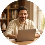 Friendly creator sitting at a desk with a laptop, warm natural light, bookshelf in background